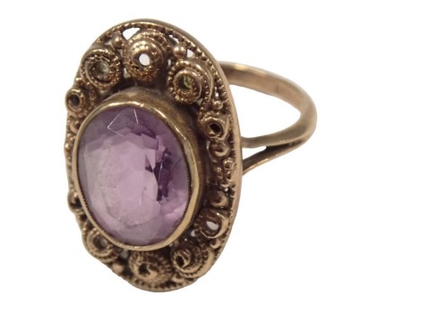 A 9ct gold amethyst dress ring, the oval amethyst in rub over setting, with oval shield with raised scroll design and V splayed shoulders, ring size P½, 5.6g all in.