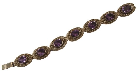 A 9ct gold and amethyst bracelet, with seven oval panel design, each centred with oval amethyst, in a rub over setting, pierced and scroll outer border, 20cm long, 34.9g all in.