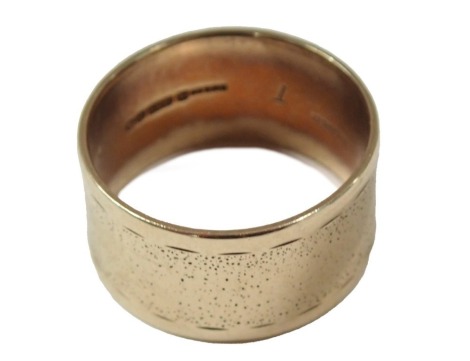 A 9ct gold wedding band, of patterned rubbed design, 12mm wide, London 1973, ring size T½, 6.3g all in.