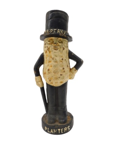 A cast iron money box, modelled in the form of a peanut man, painted in cream and black wearing a top hat, the base named, 28cm high.