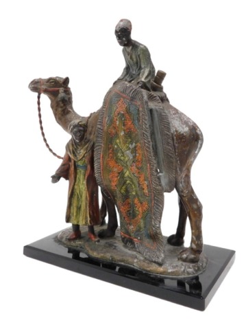 An early 20thC Cold painted spelter table lighter, modelled in the form of a camel beside two rug salesmen, on rectangular base, 19cm high. (AF)