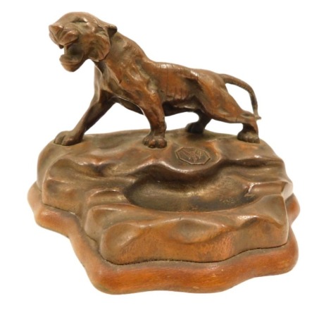 An early 20thC bronzed metal ashtray, mounted with a tiger and initials WYF, with weighted base, 17cm wide.