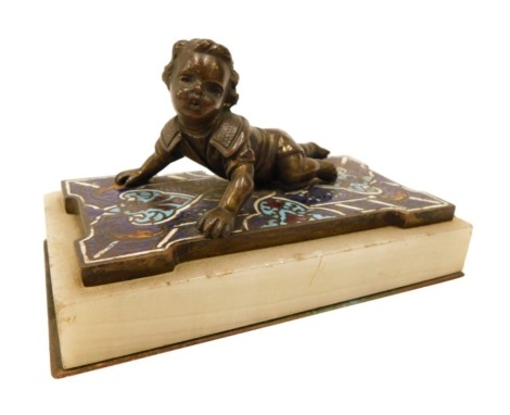 A late 19thC bronzed figure of a child lying on an Oriental carpet, the carpet with blue, red champleve enamel decoration, on onyx plinth, possibly French, 11cm wide.