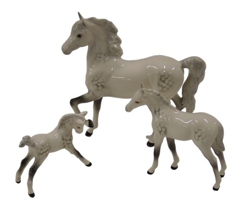 A Beswick grey prancing pony, 18cm high, and two grey foals. (3)