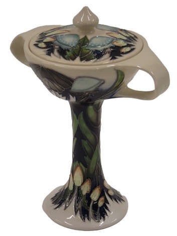 A Moorcroft ceramic two handled vase and cover, decorated with flowers and leaves on a blue ground, impressed marks to underside, copyright 2014, initials ES, 22cm high.