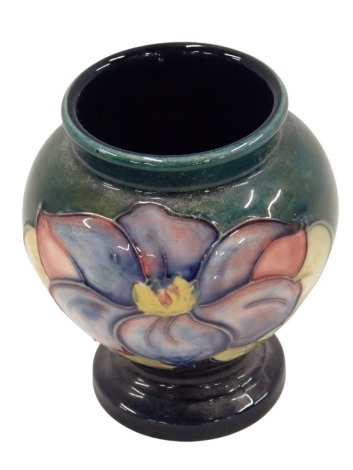 A Moorcroft vase, decorated with flowers on a green ground with blue flowers, stamp to underside, 9cm high.