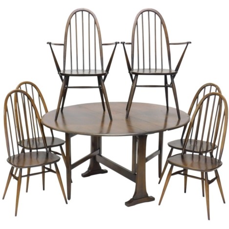 An Ercol elm oval drop leaf table, on shaped end supports, 128cm wide, and six spindle back chairs, each with a solid seat and arched back, two with arms.