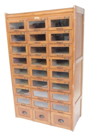 A set of oak Levine shop drawers, the drawers mainly with a glazed panel, and a cast metal handle, and three drawers with solid handles and panels, 165cm high, 102cm wide.