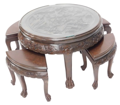 A nest of five Eastern hardwood tables, the larger circular top carved with warriors, rocks, trees, buildings, etc., on cabriole legs, with paw feet, 75cm diameter.