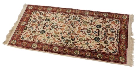 A Persian carpet, decorated with an all over design of scrolls, flowers, and leaves, in mainly blue on a red ground, with cream and blue spandrels, one wide, six narrow borders, 377cm x 266cm.