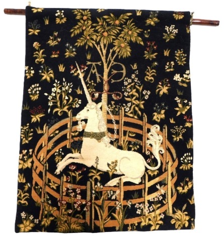 A 20thC Aubusson style hanging tapestry, with unicorn in brass ring, decorated with palm trees, on a wooden rod, with brass mounts, 60cm x 47cm.