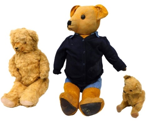 Three teddy bears, comprising a 20thC mohair bear with amber glass eyes, and pad feet and hands, 31cm high, a fluffy 20thC mohair bear with amber glass eyes, 56cm high, and a straw filled bear, 71cm high. (3)