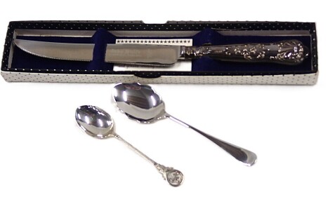 A small group of silverware, comprising Isle of Man silver spoon, spoon with petalated border, 1oz, and a silver handled and stainless steel blade cake knife. (3)