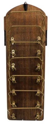 A 1930s oak ebonised and brass newspaper rack, wall mounted, with seven brass holders, 66cm high.