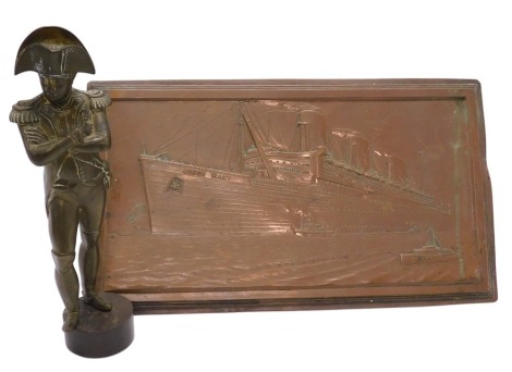 A brass figure of Emperor Napoleon I, in standing pose, 22cm high, together with an embossed copper plaque, of rectangular section, decorated with the Liner Queen Mary, 19cm x 33.5cm. (2)