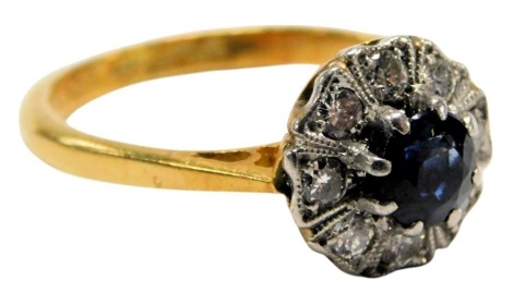 A sapphire and diamond flower head ring, the central brilliant cut sapphire in a surround of eight diamonds, in a yellow and white metal shank, stamped 18ct and plat, size J, 2.7g.