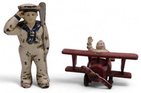 A vintage Michelin cast iron man in a biplane advertising figure, 13cm wide, together with a cast iron money box, modelled as a sailor holding an oar, 13.5cm high. (2)