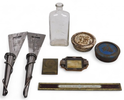 A pair of contemporary steel wall mounted candle holders, 39cm high, two 4lb cast iron weights, a Blue Band Margarine advertising ruler, Boots chemist bottle, pair of French Art Deco copper ashtrays, and a German brass plaque.