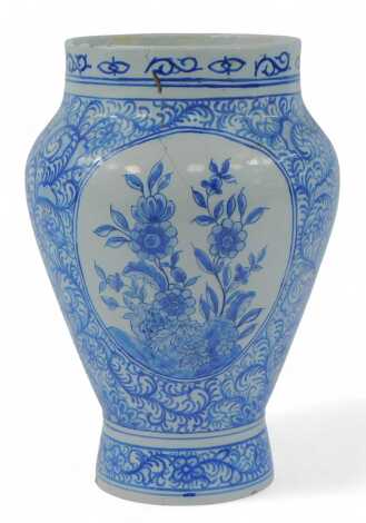 A 19thC Delft tin glazed drug jar, of baluster form, decorated in blue with reserves of flowers against a leaf and floral decorated ground, marks to underside, 26cm high. (AF)