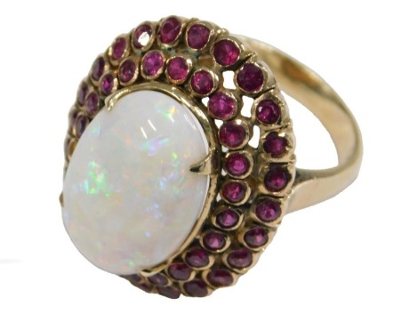 A gold opal and ruby ring, in a basket setting, the opal in a double row surround of rubies, one stone lacking, shank stamped 750, size O, 11.2g.