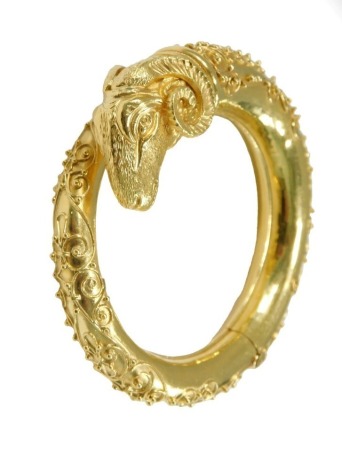 A torc bangle, with a ram's head terminal, and filigree scroll decoration, on a hinged mechanism, stamped 750, 69g.