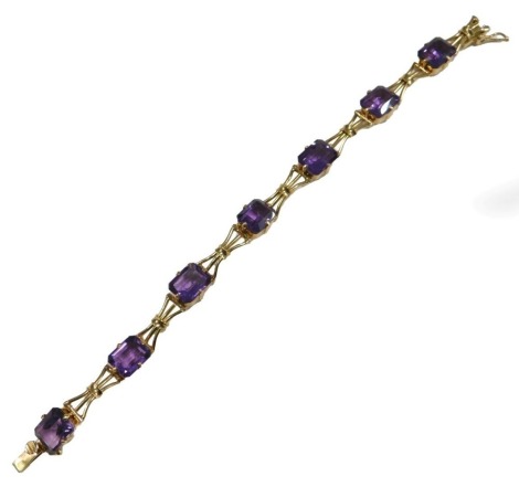 An amethyst seven stone bracelet, in yellow metal, the stone interspersed with tied bows, on a snap clasp, unmarked, 16.8g.