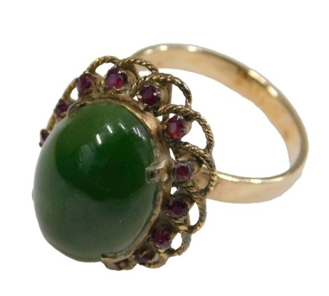 A gold jade and ruby ring, the oval cabochon jade in a surround of small rubies, within a basket setting, shank indistinctly stamped, size O, 5.4g.