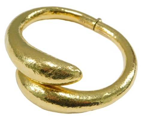 An Ilias Lalaounis gold bangle, in a textured crossover design, with a hinged mechanism, stamped 750, 51.5g.