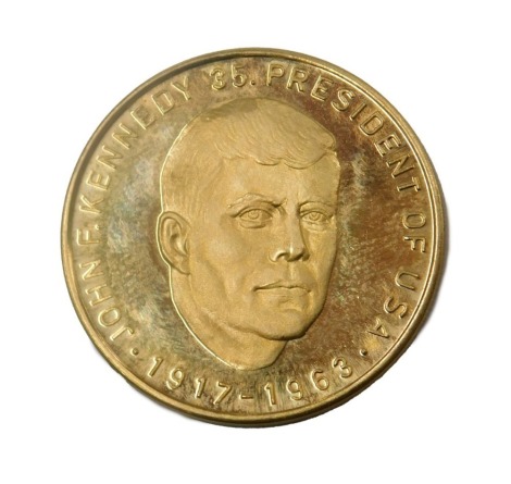 A John F Kennedy 35th President of the USA 1917-1963 yellow metal medallion or coin, the reverse decorated with a crest, stamped 0.900, 8g.