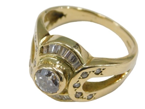 A modern 18ct gold diamond ring, with a central brilliant cut diamond of approximately 0.95cts, within borders of fourteen baguette cut diamonds, and with tiny diamonds to the shoulders, rub over set in yellow gold, 8.74g all in.