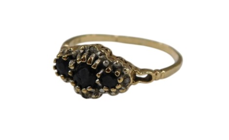 A 9ct gold and sapphire three stone ring, in a surround of diamonds, size P, 1.8g.