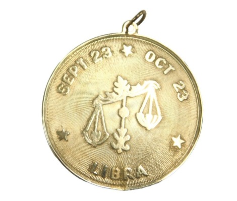 A Libra pendant, embossed with scales and Sept 23-Oct 23, stamped 14k, 4.9g.