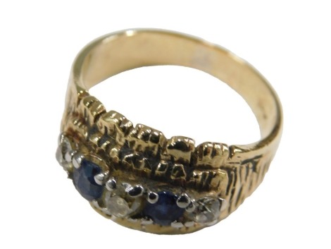 A sapphire and diamond five stone ring, mounted on a stepped textured shank, yellow metal, stamped 9c, size R½, 6.8g.