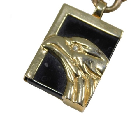 A 9ct gold neck chain, on a lobster claw clasp, with a suspended pendant, embossed with an eagles head, with diamond set eye, on black onyx, within a yellow metal frame, engraved Bill Blass, 14k, 33.7g all in.