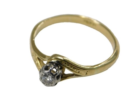 A diamond solitaire ring, in a high claw crossover setting, yellow metal, stamped 18ct, size L½, approx 1/16ct, 2.2g.