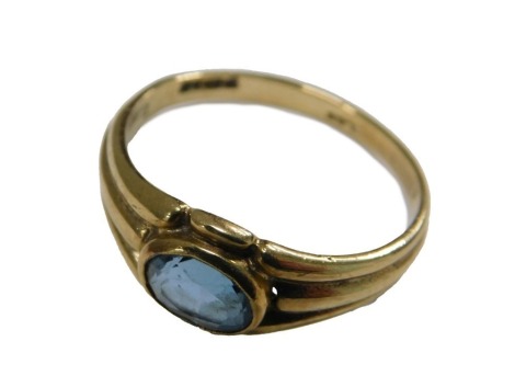 A 9ct gold and topaz ring, the oval cut stone within channelled shoulders, size L½, 2.1g all in.