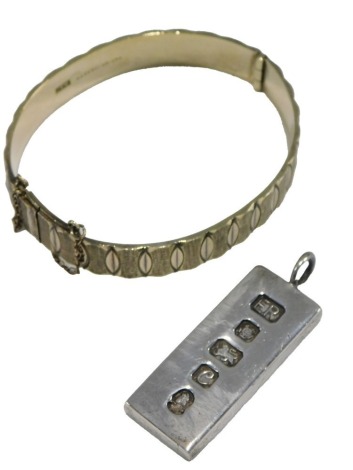 A silver bangle, in a textured interlock circular design, on a snap clasp, with safety chain as fitted, together with a 1oz ingot pendant, 1.96oz.