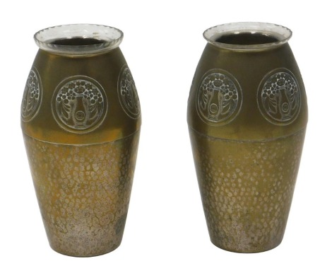 A pair of Continental aesthetic movement silver plated brass vases, each decorated with roundels, marks indistinct, and with later glass inserts.