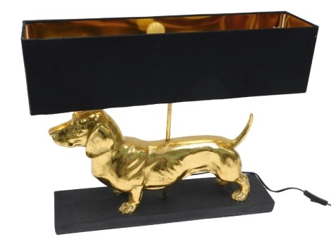 A modern table lamp, modelled in the form of a gold coloured Dachshund, with black shade and ebonised base, 55cm wide.