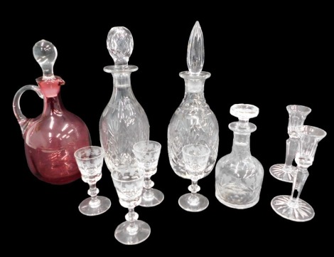 A collection of glass, to include two crystal decanters and stoppers, a cranberry tinted claret jug, with clear handle and stopper, a pair of candlesticks, a small spirit decanter, and six sherry glasses, each engraved with grapes and vines, decorated wit