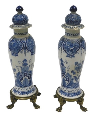 A pair of Delft blue and white vases, each with associated brass stands, 32cm high overall. (AF)