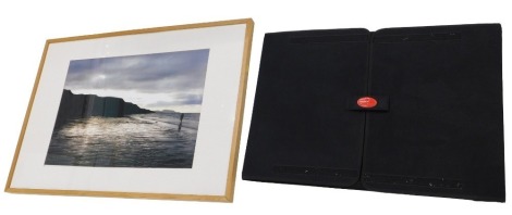 A coloured coastal photograph, framed, 49cm x 70cm, and an artist's folio.