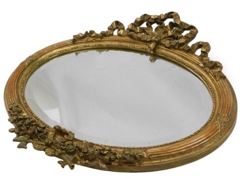 A gilt gesso oval wall mirror, the base decorated with ribbons and flowers, etc., with a bevelled mirror plate, 46cm high, 70cm wide.