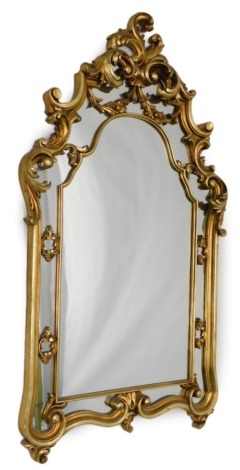 A gilt wall mirror, the arch frame decorated with scrolls and leaves, 130cm high, 69cm wide.