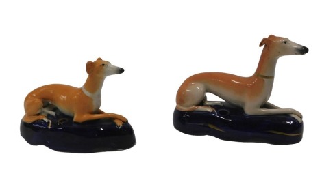 Two similar late Staffordshire Greyhound inkwells, each in the recumbent pose, on blue ovoid bases 16cm and 14cm long respectively.