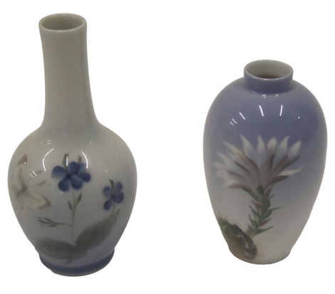 Two Royal Copenhagen porcelain vases, to include a bottle shaped vase decorated with butterflies and flowers, a bullet shaped vase decorated with a cactus, printed marks and handwritten marks to underside, 14cm and 11cm high respectively.