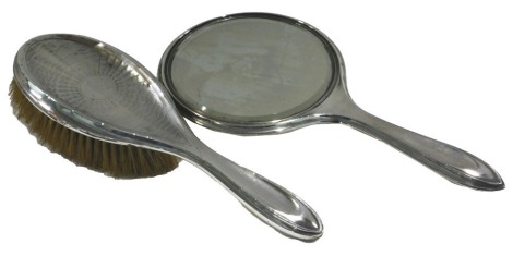 An engine turned silver dressing table mirror and a brush, early 20thC marks indistinct. (2)