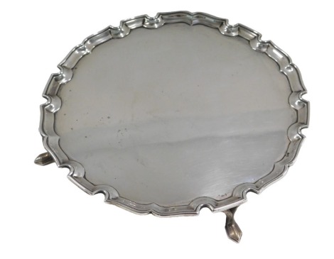 A George V silver salver, with piecrust border, on scroll feet, London 1931, 13.56oz, 21cm diameter.