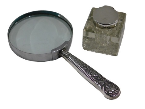 A chrome plated magnifying glass, with silver handle, decorated with grapes and vines, and an inkwell with silver lid. (2)