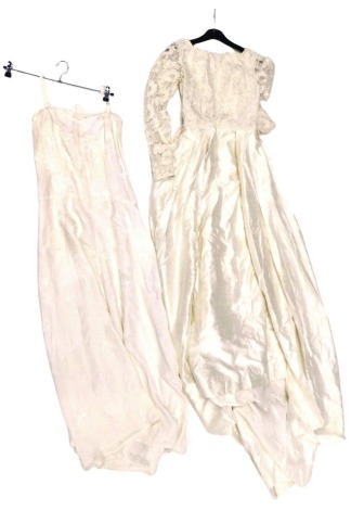 A 1950s wedding dress, with floral rosette netted bodice, straight skirt, with integrated train, waist measurement 29cm when laid flat, together with a silk underdress or night gown.